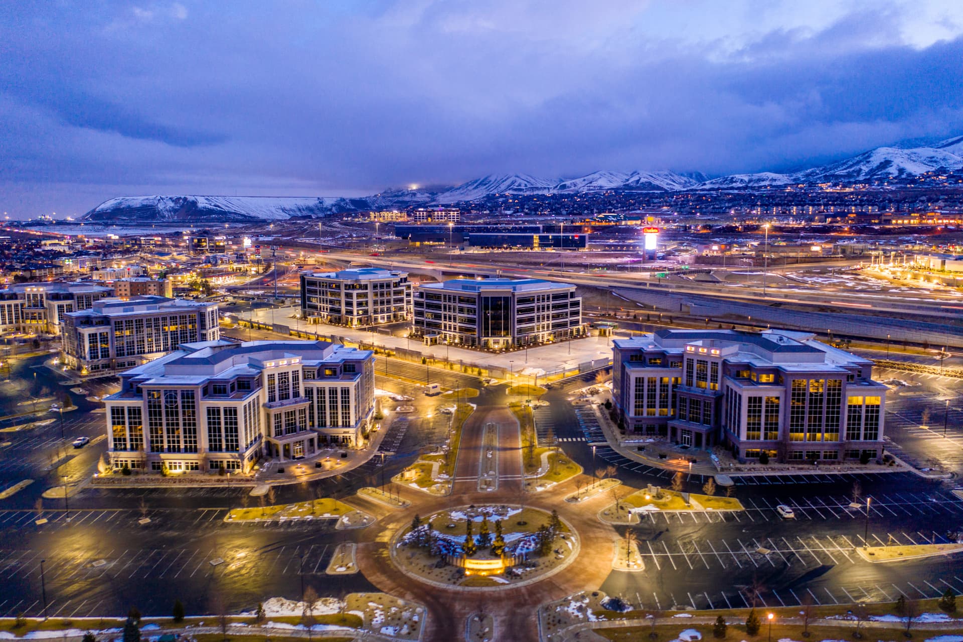 Aerial evening view of commercial buildings in Lehi, Utah with snow-capped mountains