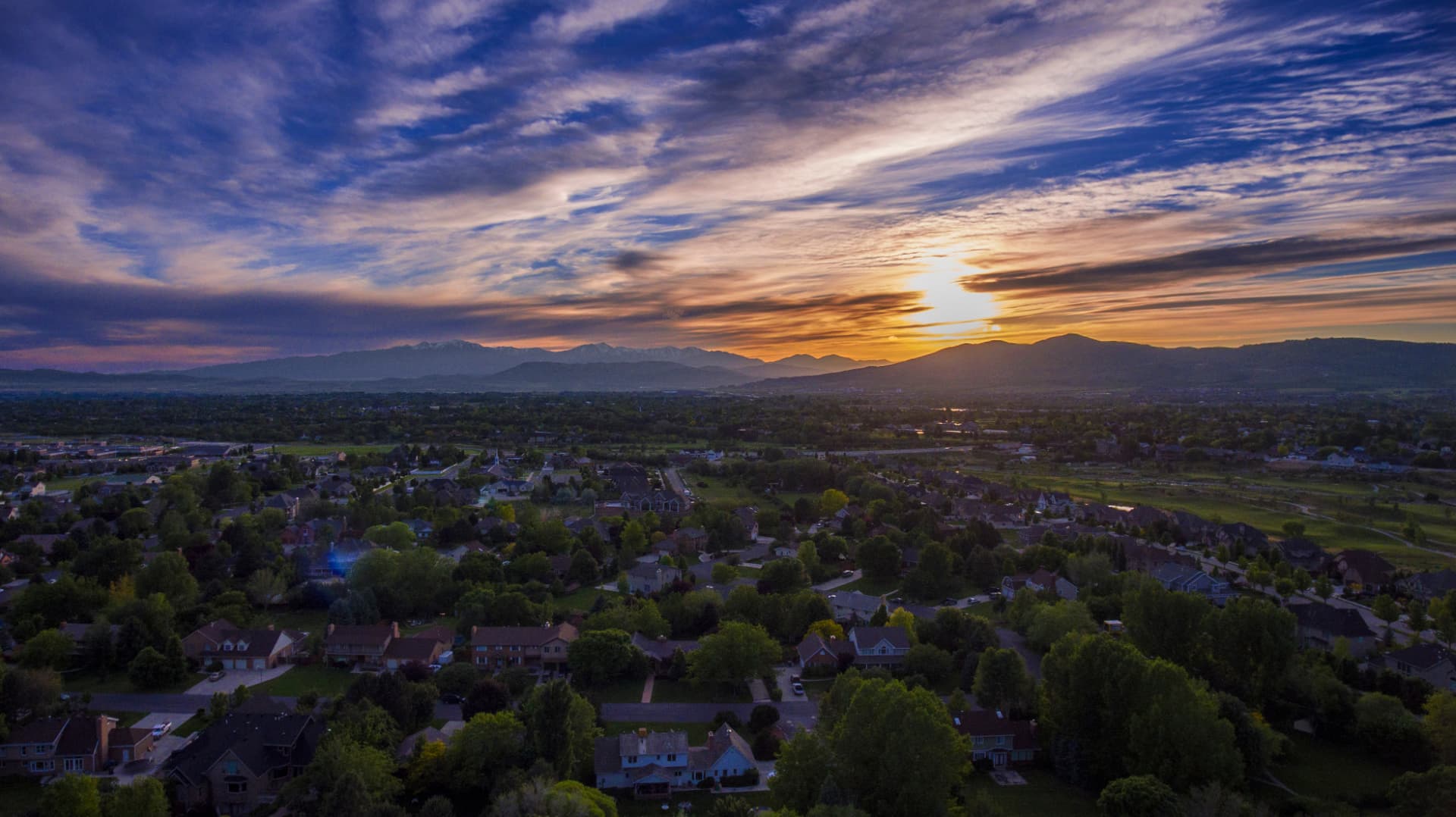 Aerial sunset view over suburban West Valley City, Utah neighborhoods and mountains