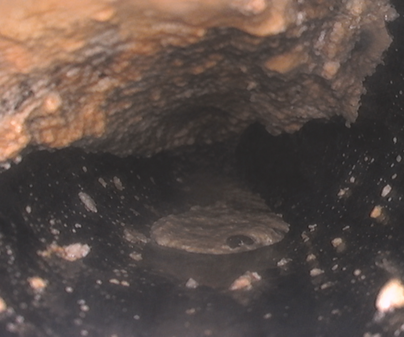 Interior camera view of a sewer pipe before hydro jetting, showing heavy scale and buildup restricting flow